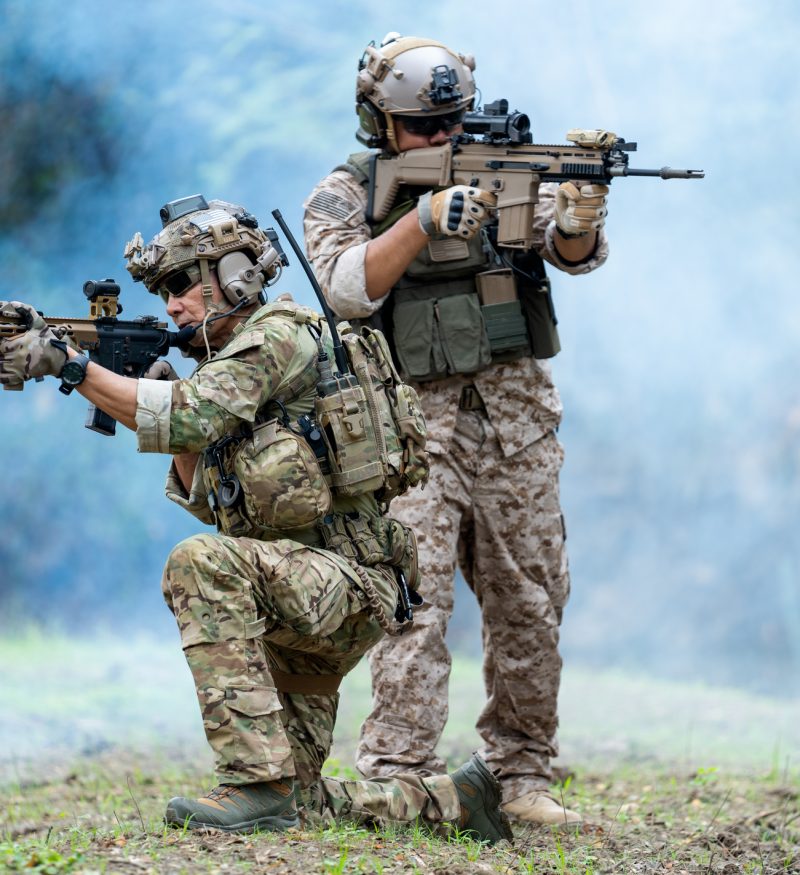 Militaries or soldiers stay in battlefield near the river with one sit down and one stand and point gun forward direction during outdoor practice. Militaries or soldiers stay in battlefield near the river with one sit down and one stand and point gun forward direction during outdoor practice.